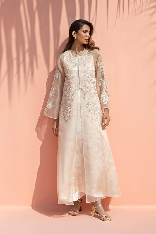 Woman wearing a light pink embroidered outfit against a peach background