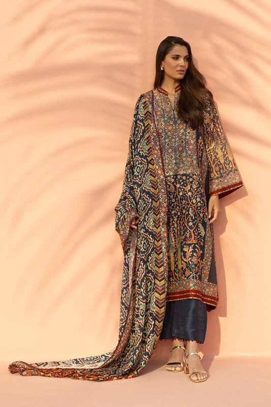 Woman wearing a patterned dress with a long scarf against a peach background