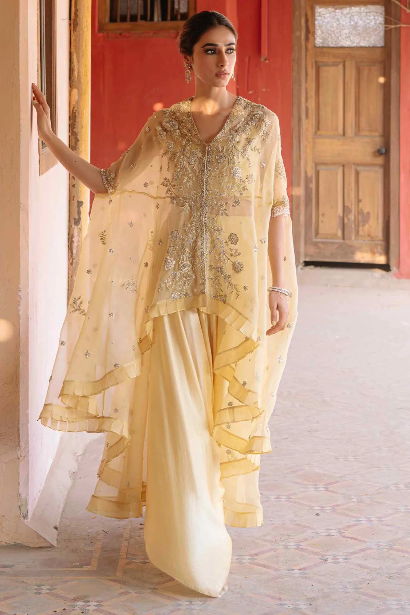 Woman in a traditional outfit with intricate designs in a decorated interior setting
