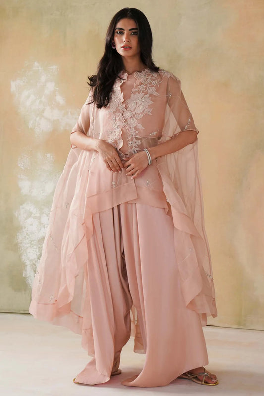 Woman wearing a light pink traditional outfit with floral embroidery against a neutral background