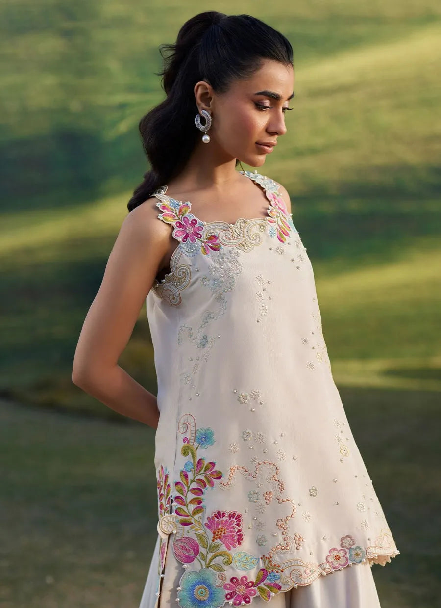 Woman wearing a white embroidered dress with floral patterns in a natural setting