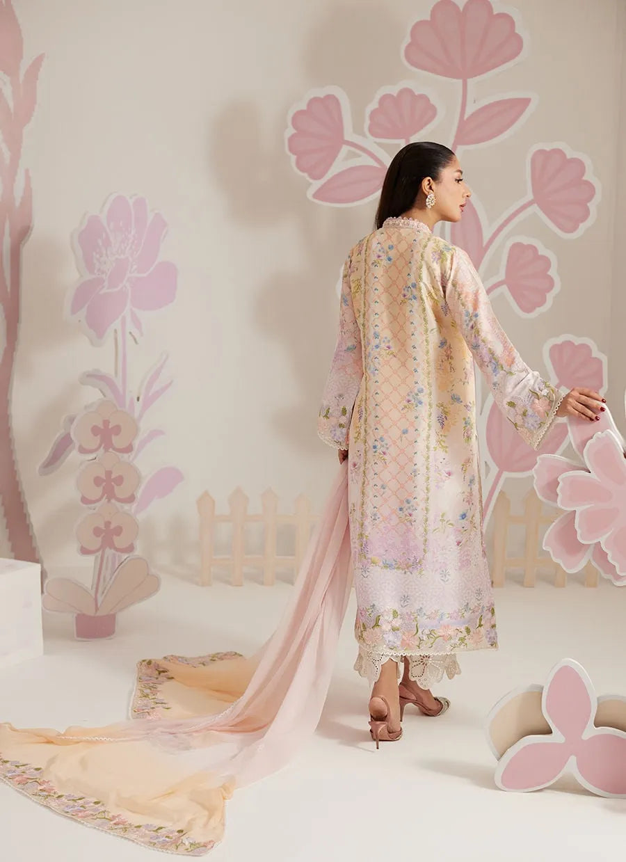 Woman in a floral dress standing against a decorative wall with pink floral patterns.