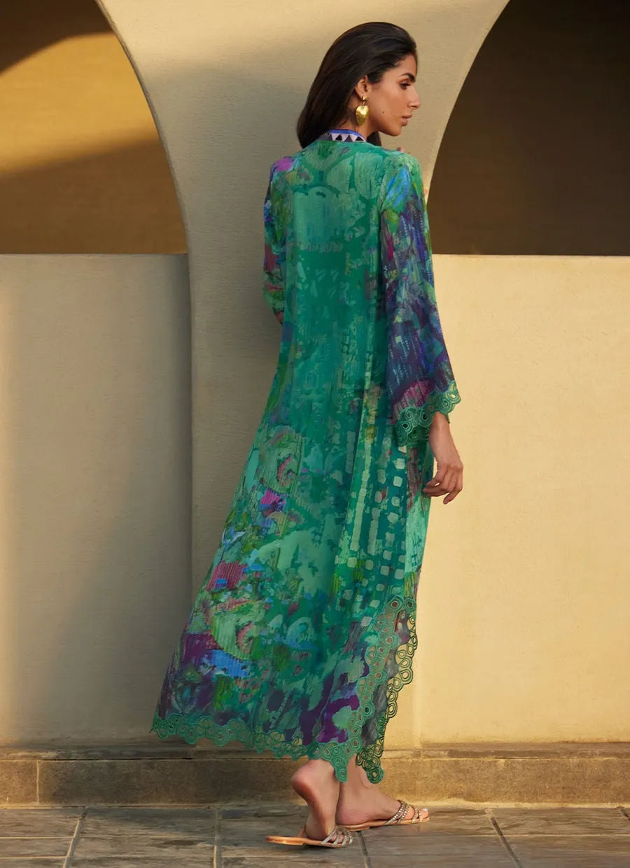 Woman wearing a colorful dress standing against a neutral wall.