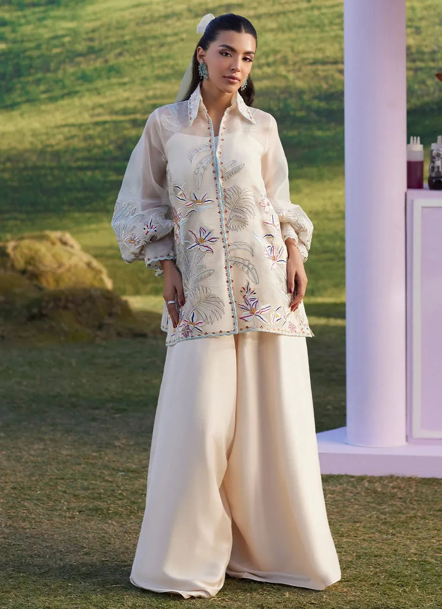 Woman in an embroidered outfit standing outdoors with a blurred background