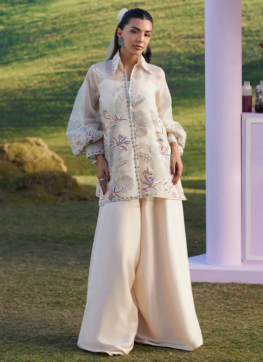 Woman in an embroidered outfit standing outdoors with a blurred background