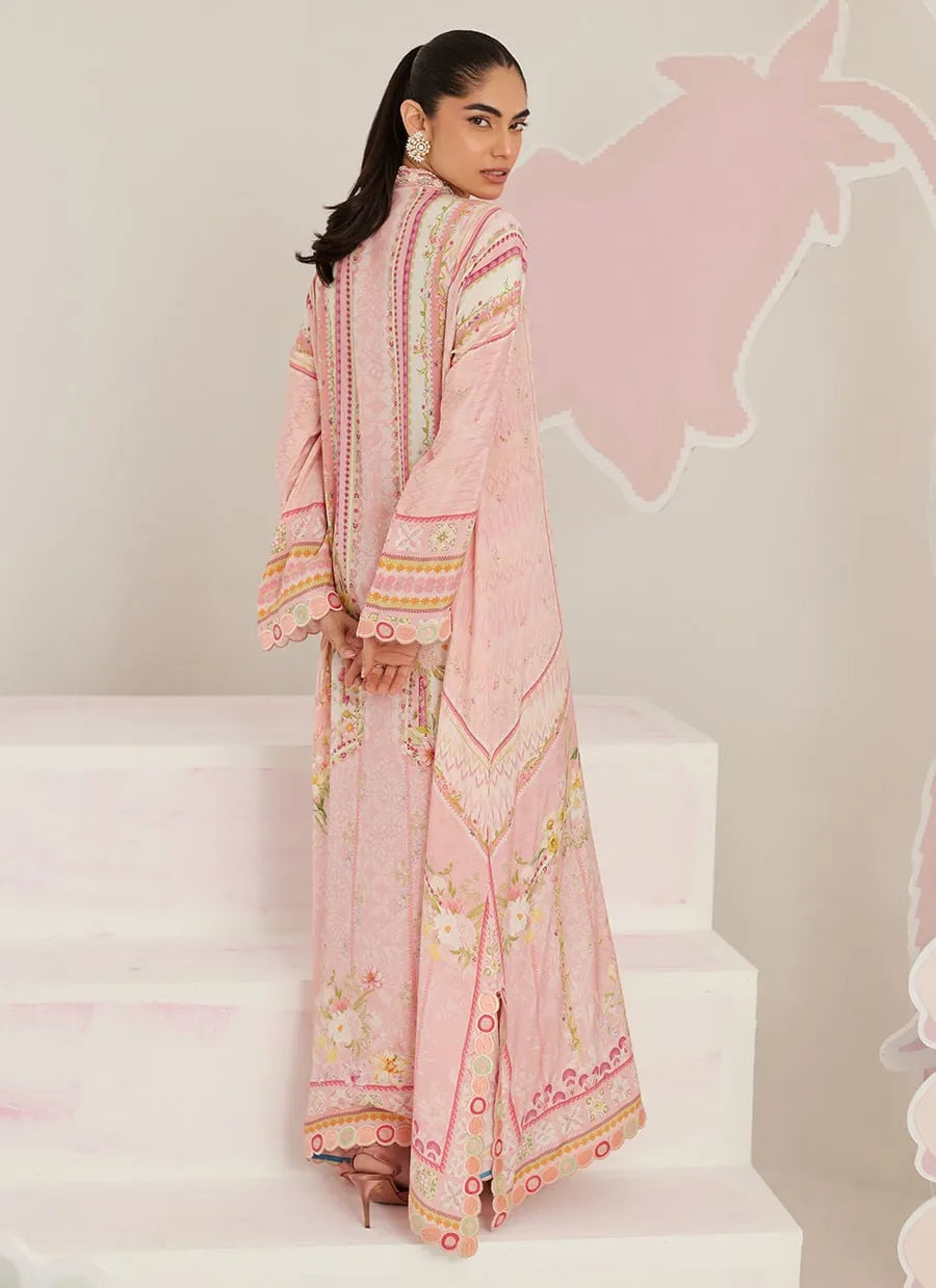 Woman in a pink embroidered outfit standing on white steps with a pink heart-shaped design in the background.