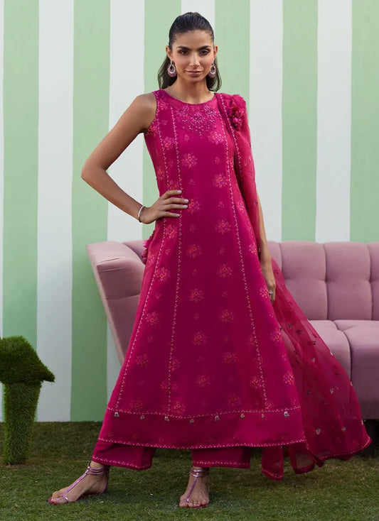 Woman in a pink traditional outfit standing in front of a striped wall with a pink couch.