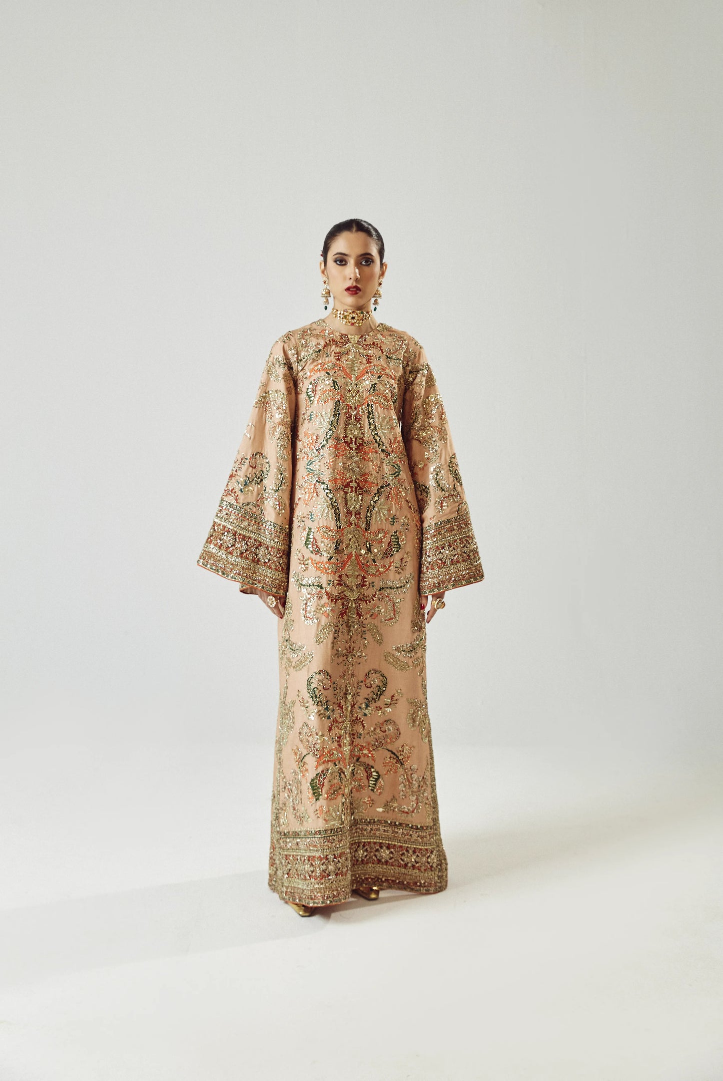 Woman wearing a long, patterned dress against a white background