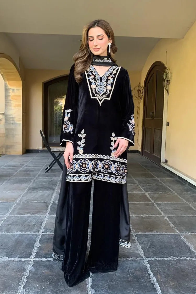 Woman wearing a black embroidered outfit standing in an outdoor setting.