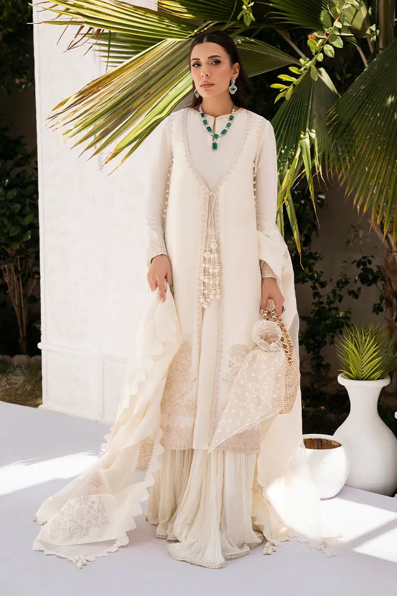 Woman in a white traditional outfit standing outdoors with greenery in the background