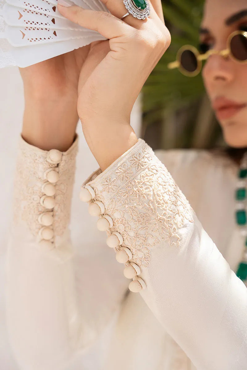 Close-up of a person wearing a white outfit with decorative sleeves and a ring.