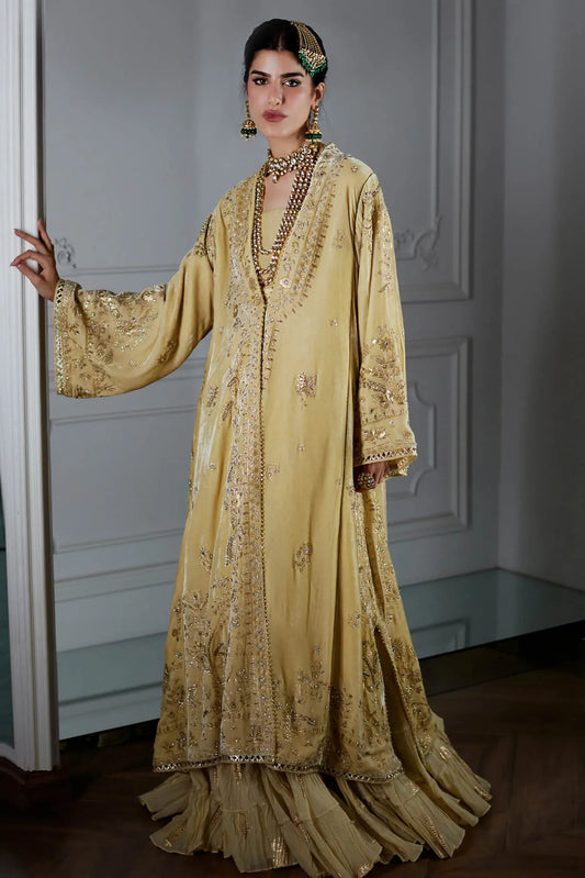 Woman wearing a traditional embroidered yellow dress in an indoor setting.