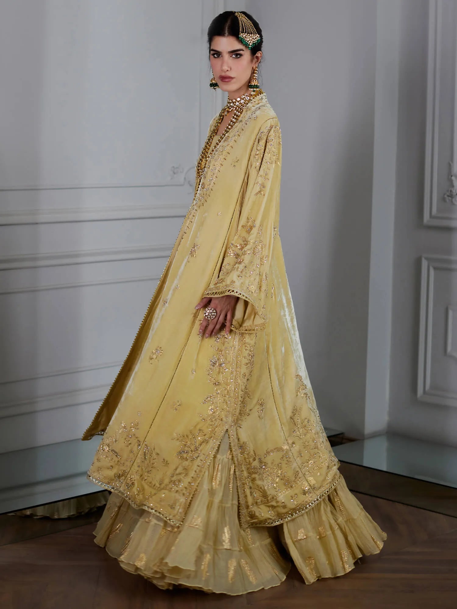 Woman wearing a yellow embroidered traditional outfit in an indoor setting