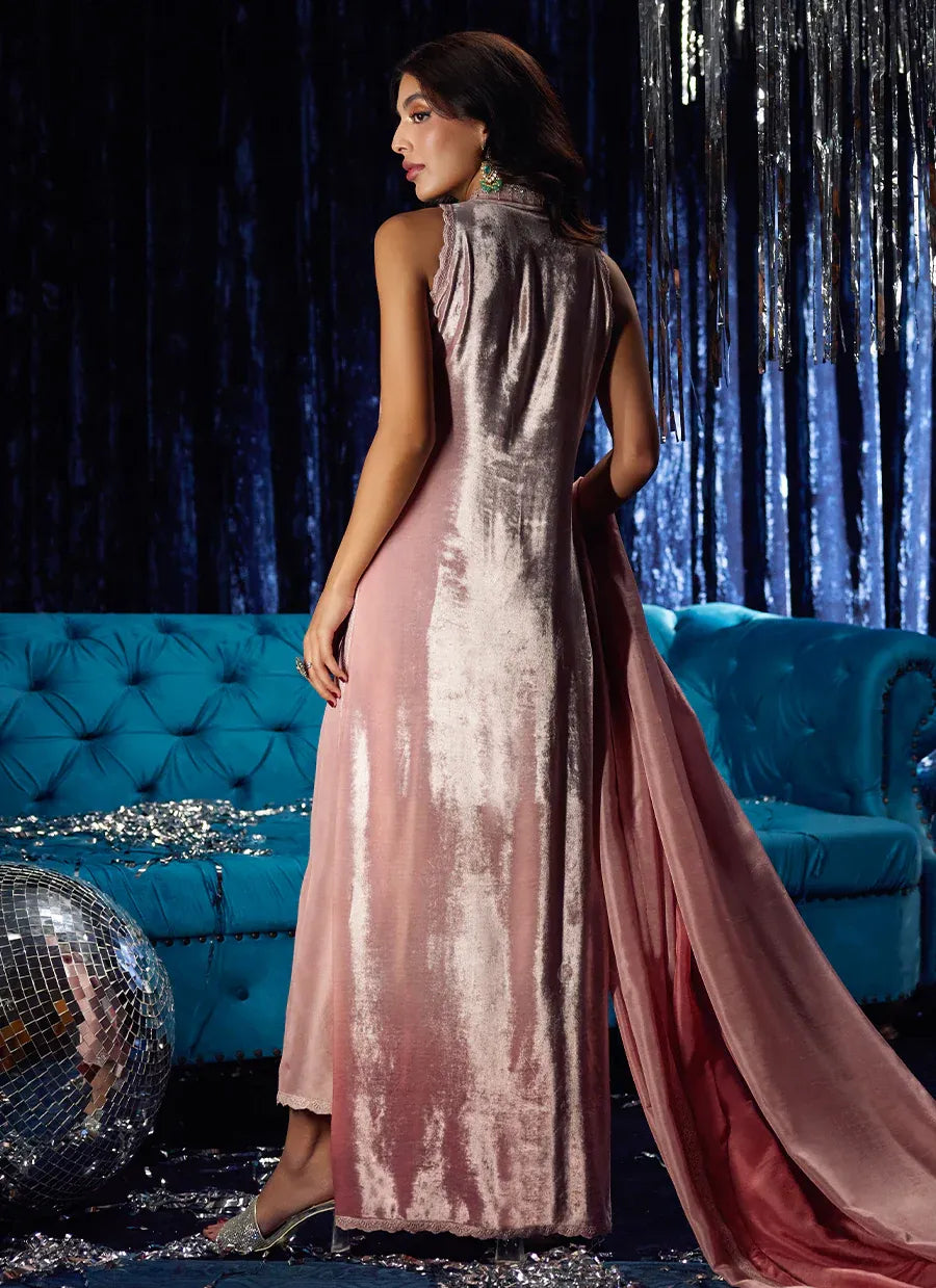 Woman in a glamorous pink and silver dress standing in front of a blue couch with decorative elements.