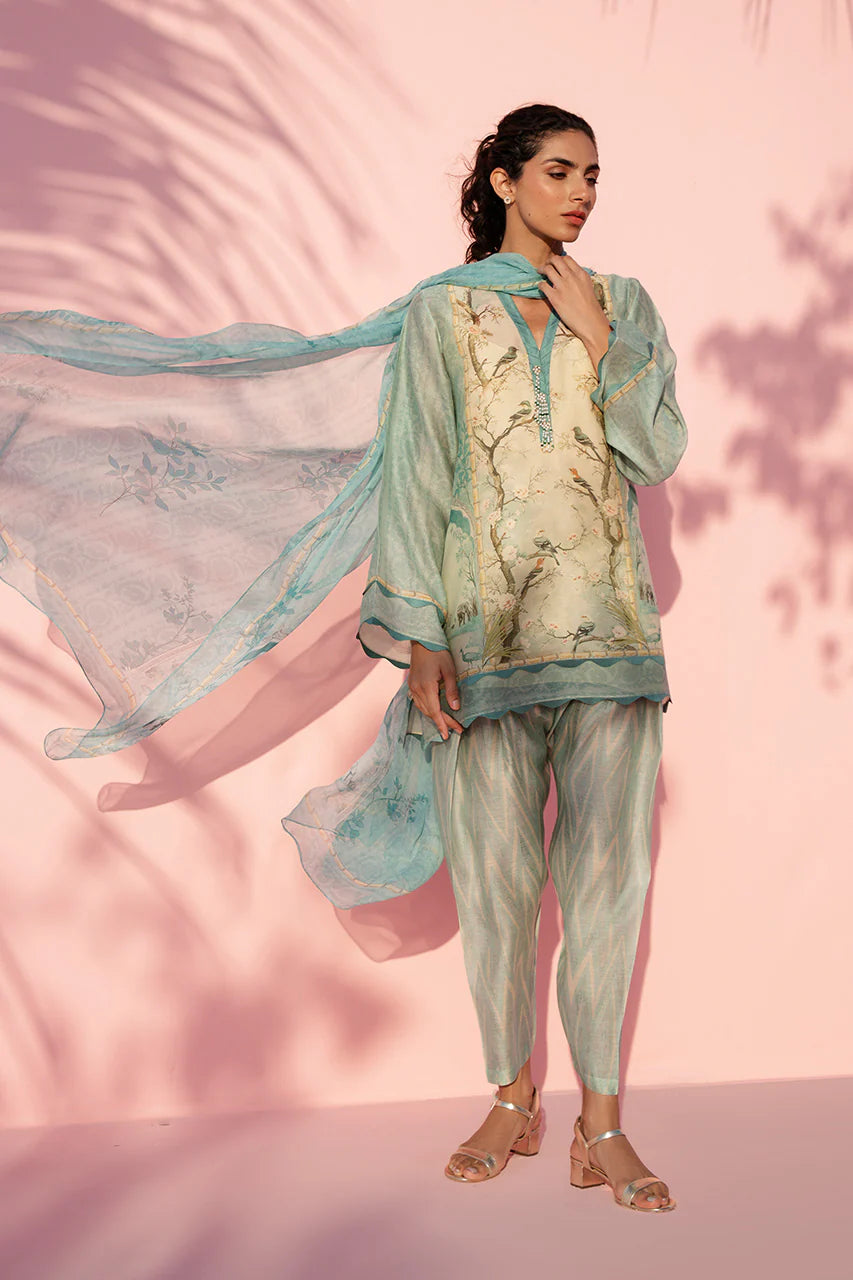 Woman in a stylish outfit with a light blue scarf against a pink background