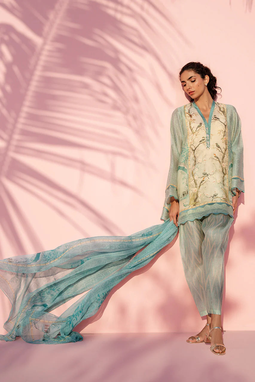 Woman in a light blue and beige traditional outfit against a pink background with palm leaf shadows.