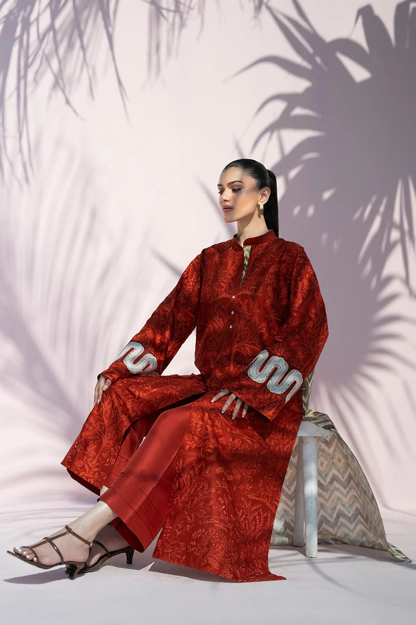 Woman in a red outfit sitting on a stool with palm leaf shadows on the wall.
