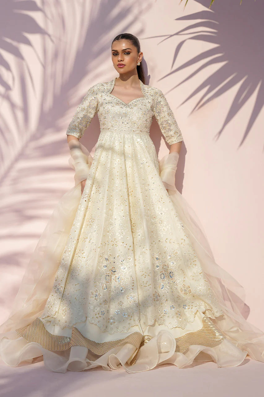 Woman wearing a white embroidered gown with a soft pink background