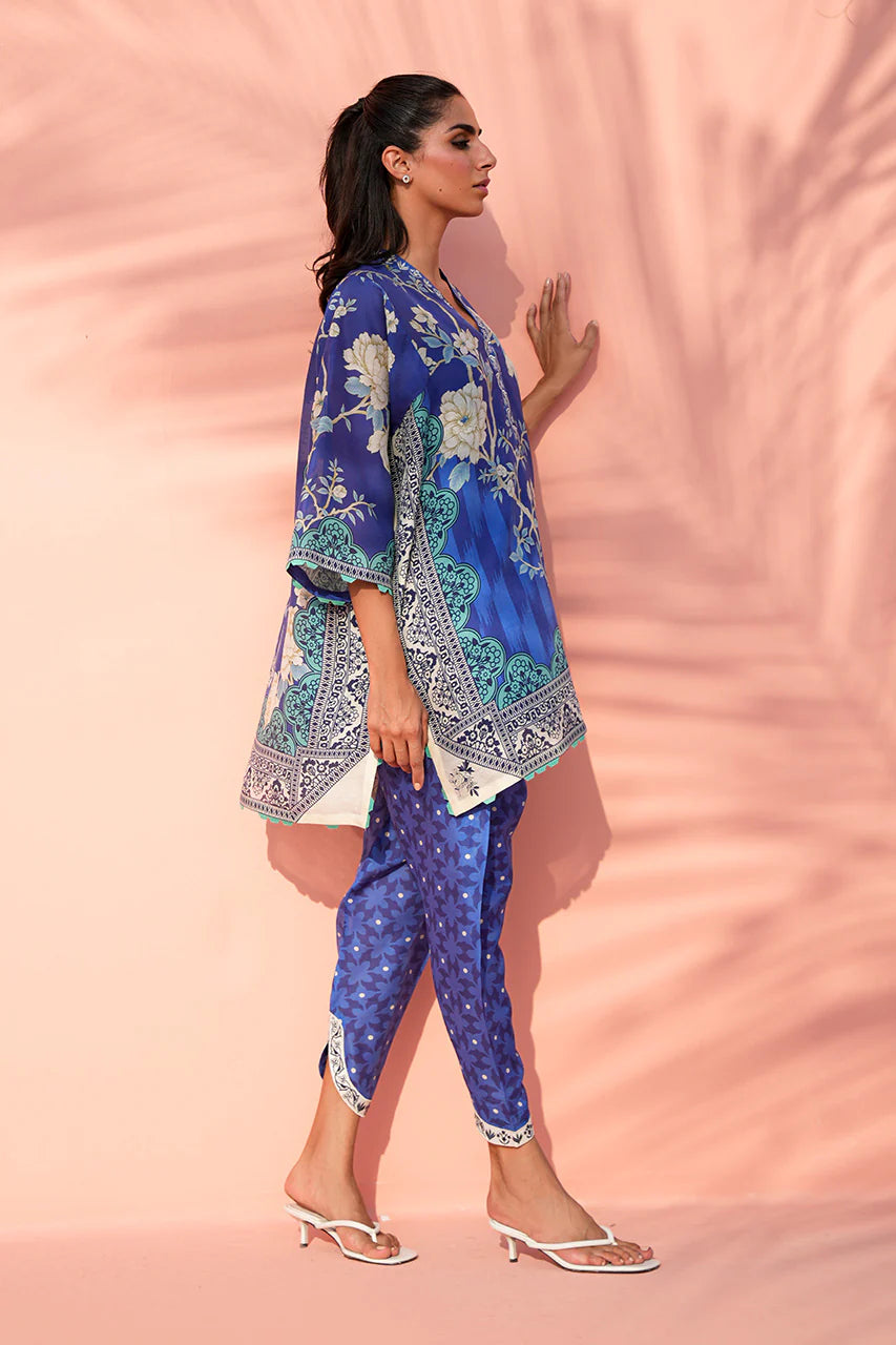 Woman wearing a blue patterned outfit against a pink background