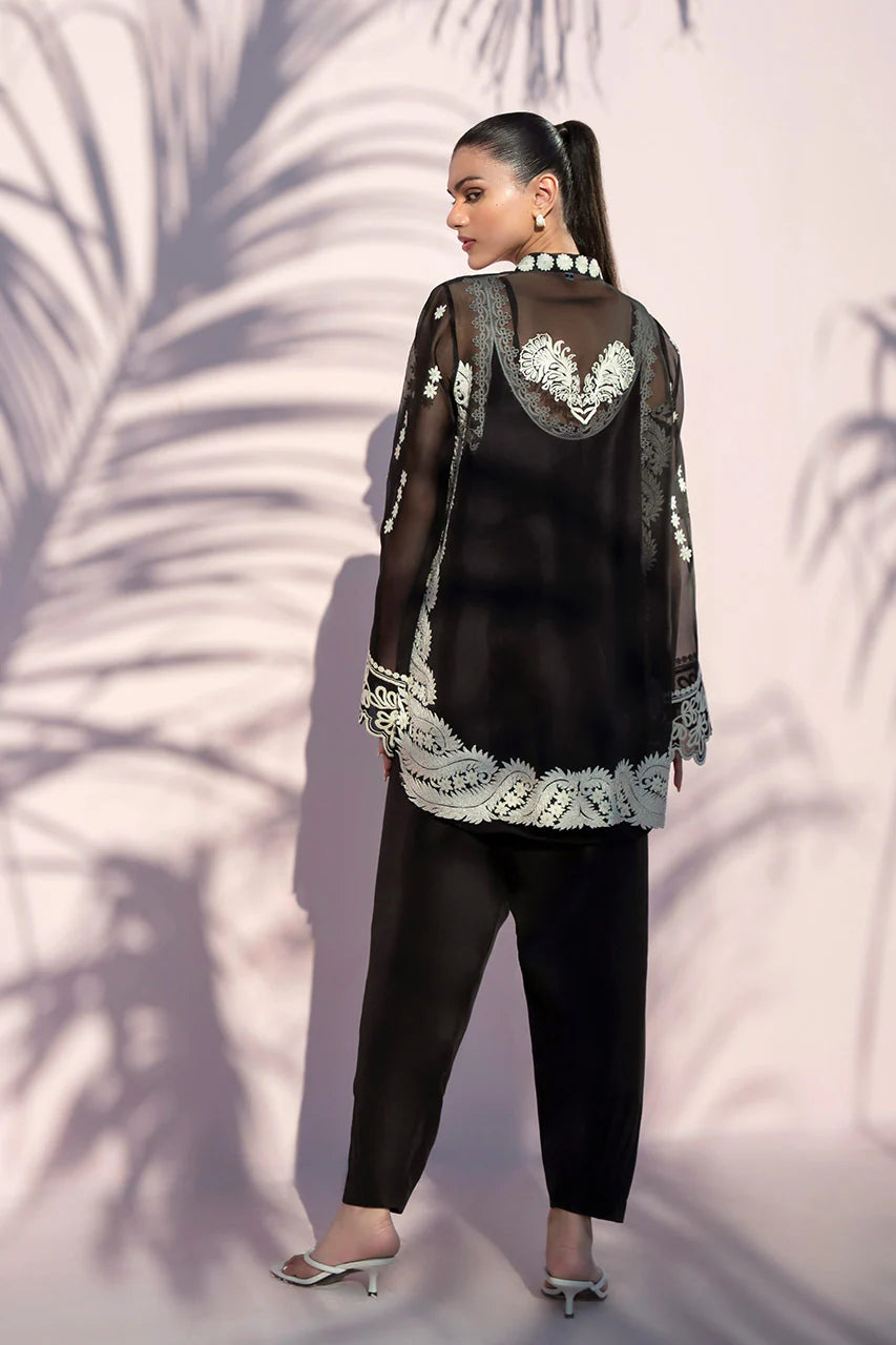 Woman wearing a black outfit with white lace details against a neutral background
