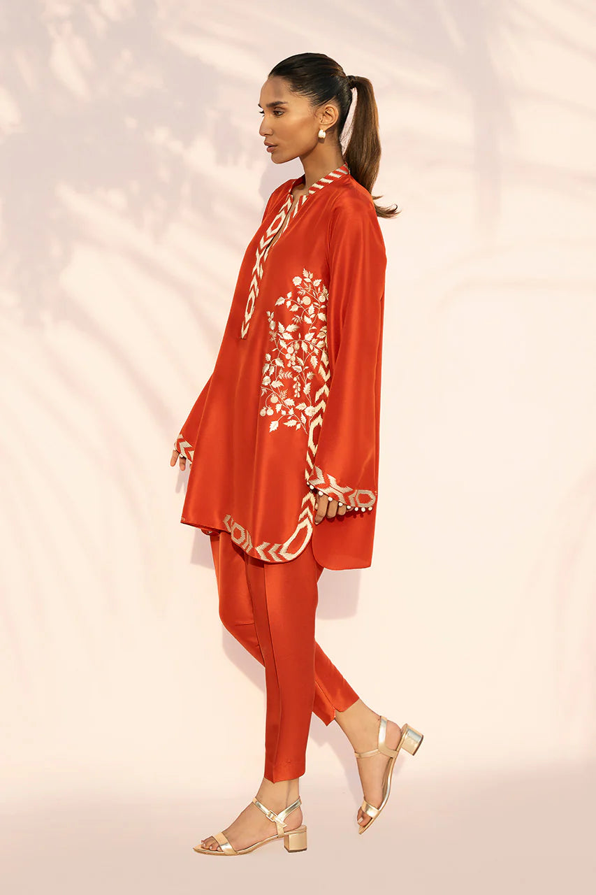 Woman wearing a red outfit with white floral embroidery on a light pink background