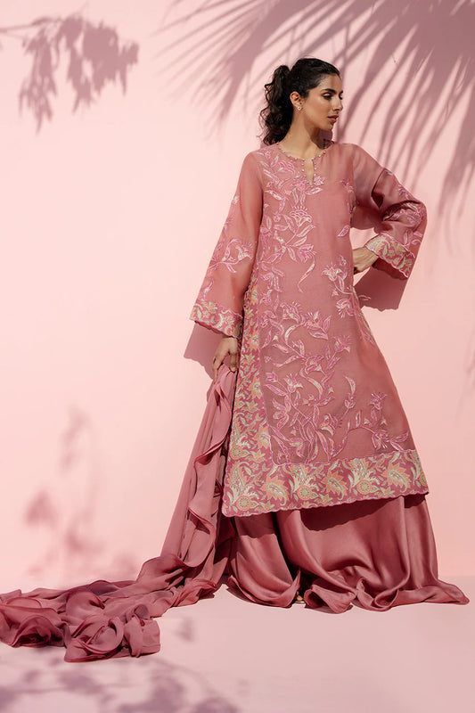Woman wearing a pink traditional outfit with floral patterns against a pink background