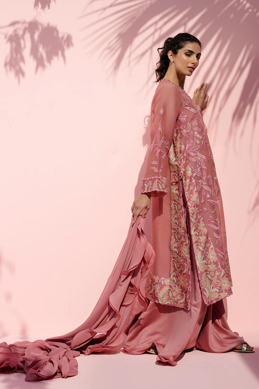 Woman in a pink traditional outfit with floral patterns against a pink background