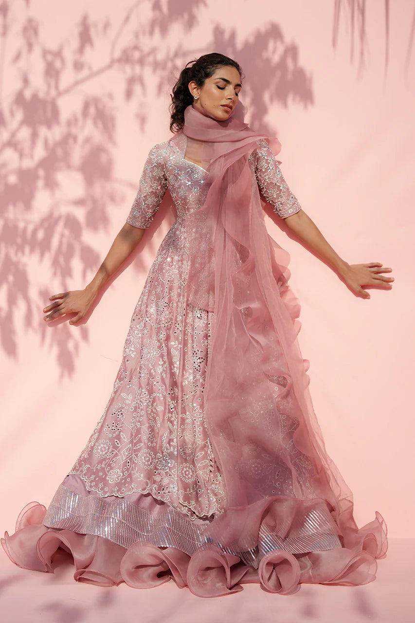 Woman wearing a pink and silver traditional outfit with a sheer dupatta against a pink background