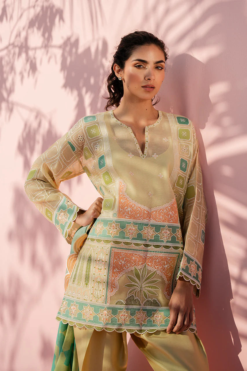Woman wearing a traditional outfit with intricate patterns against a pink wall.