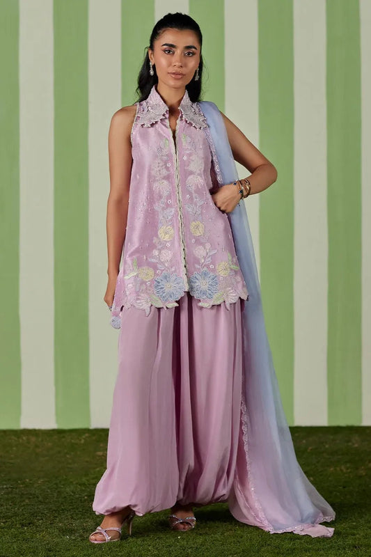 Woman wearing a pink traditional outfit with floral patterns against a green and white striped background