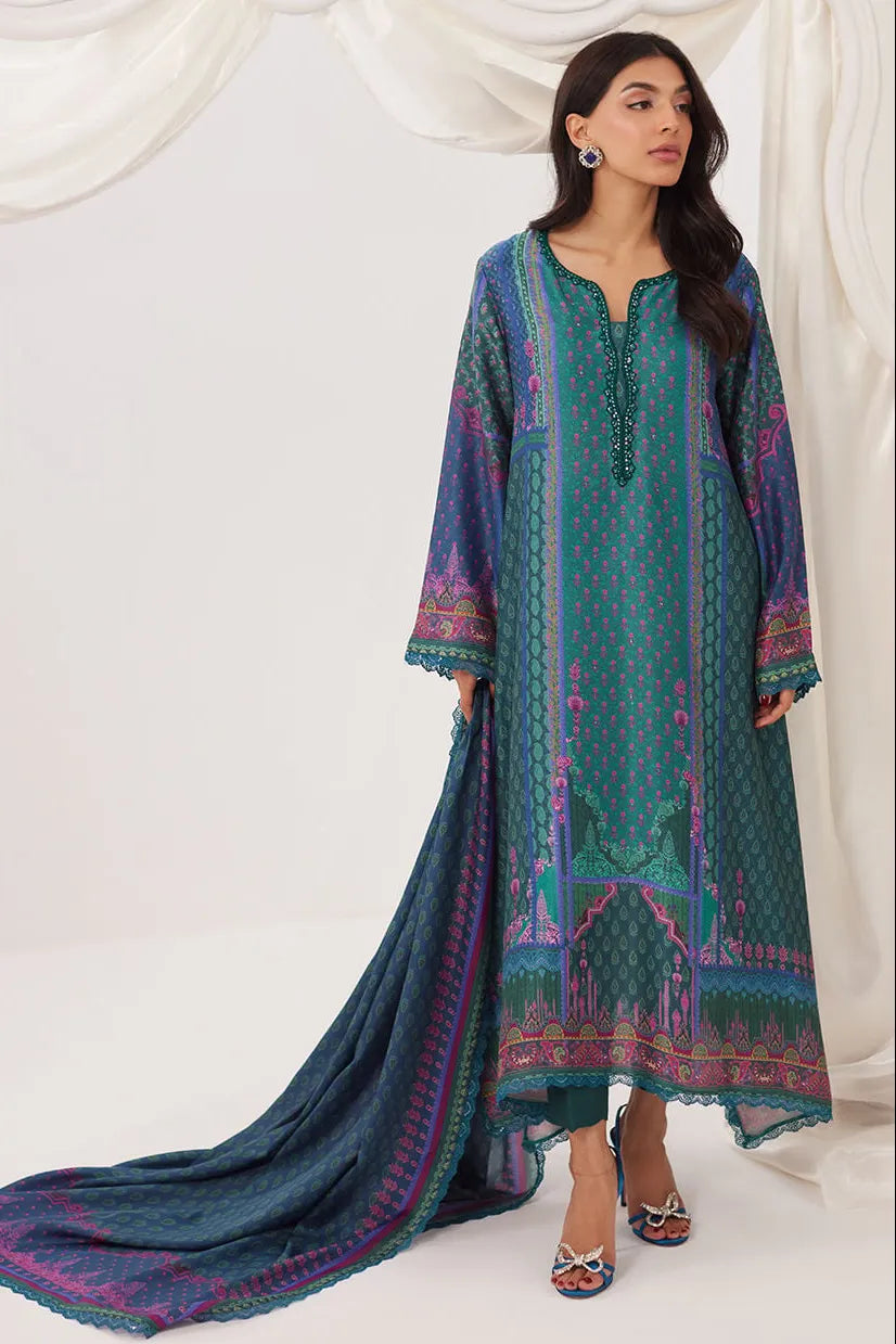 Woman wearing a blue and green embroidered traditional outfit with a white background