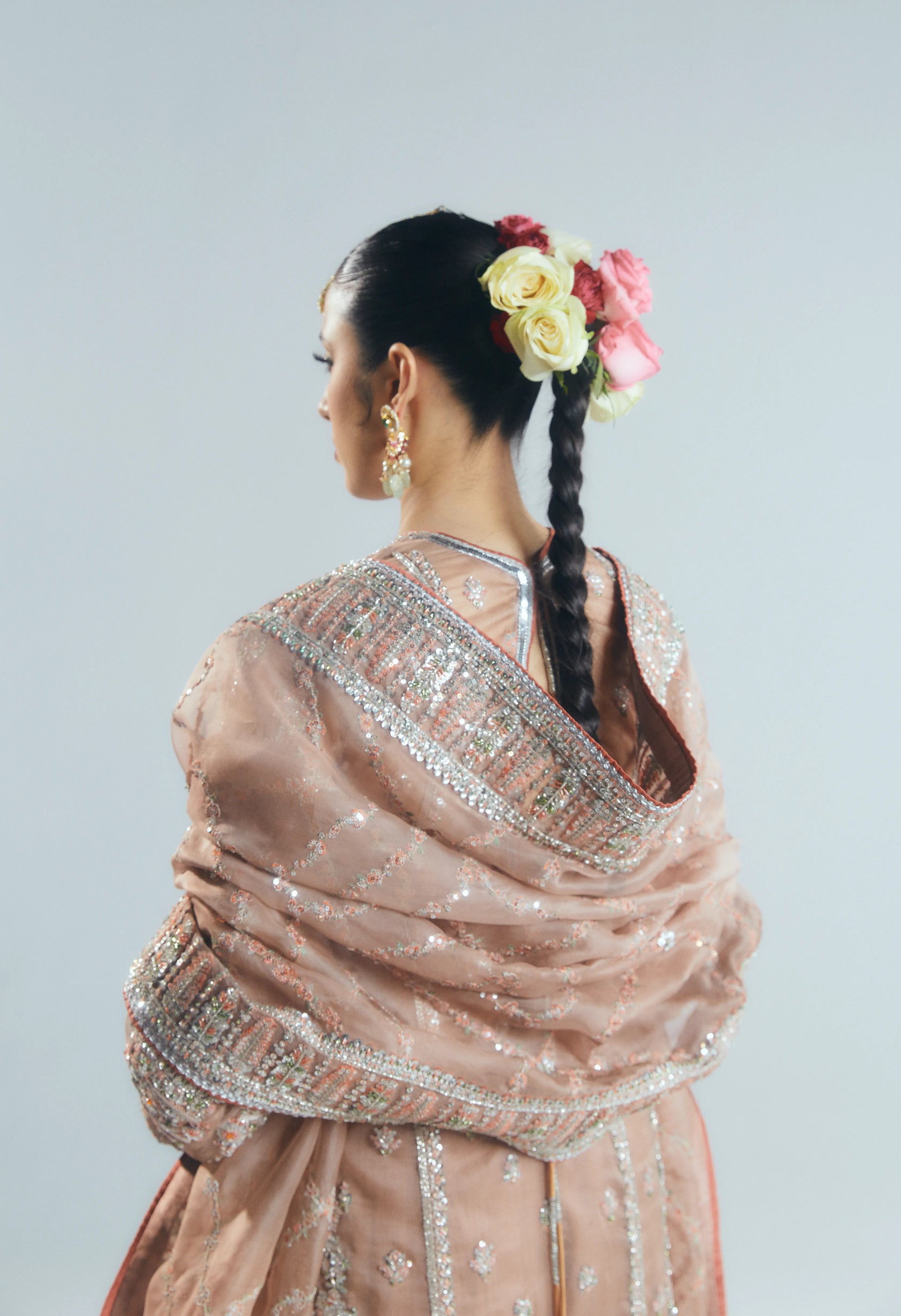 Woman wearing a traditional outfit with floral hair accessories against a plain background