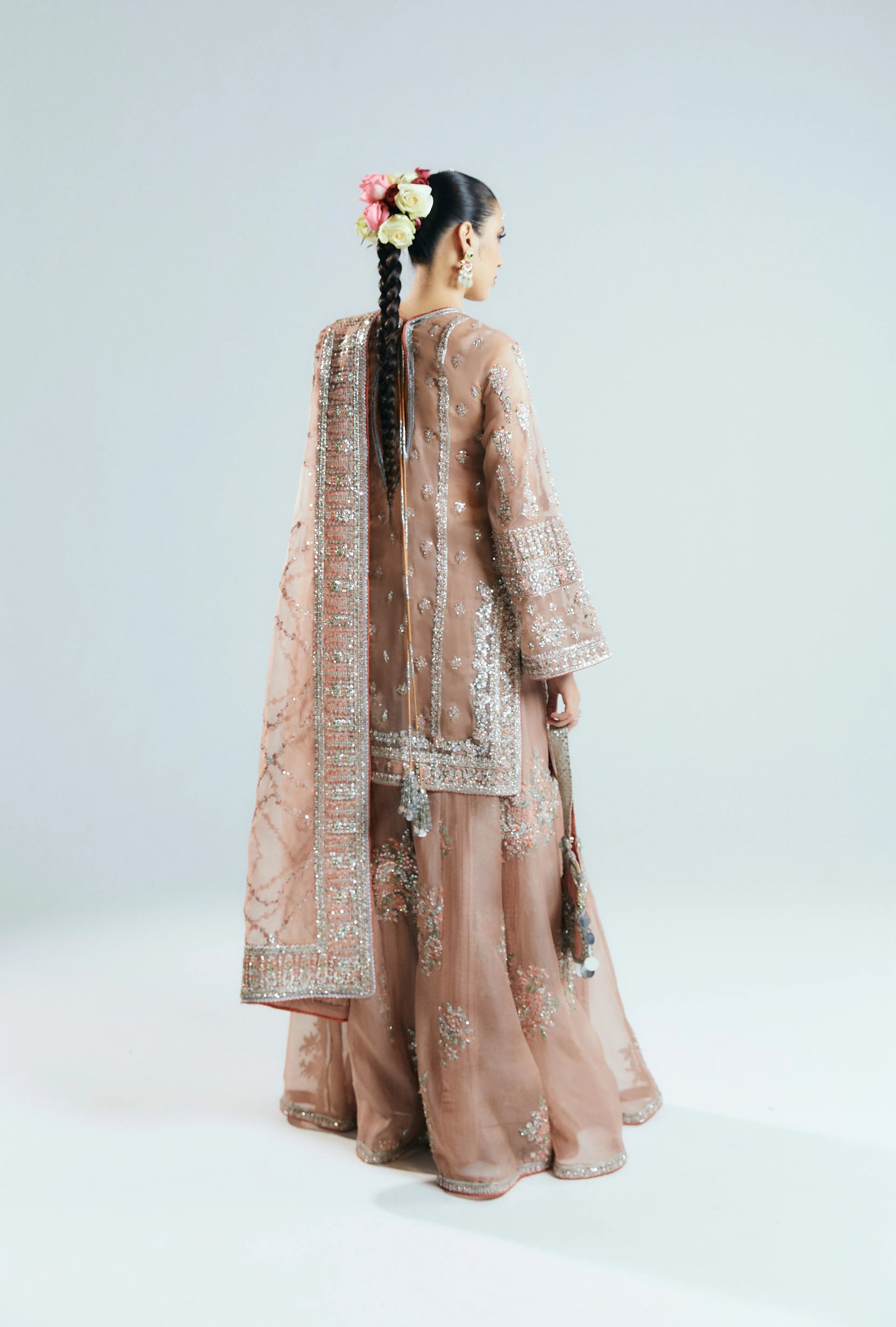 Woman wearing a traditional outfit with a sheer dupatta on a white background