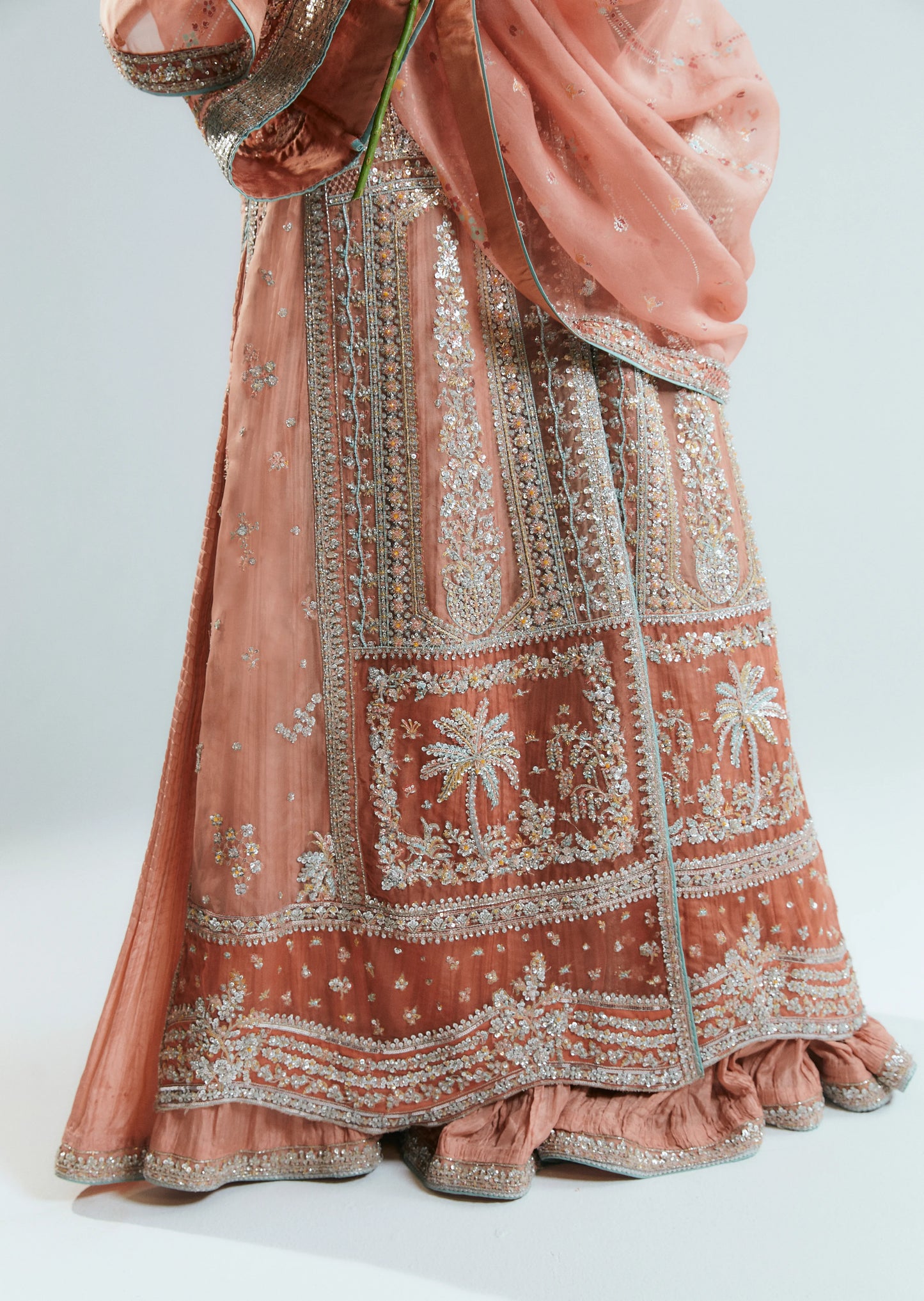 Traditional embroidered outfit with a pink and gold color scheme on a white background