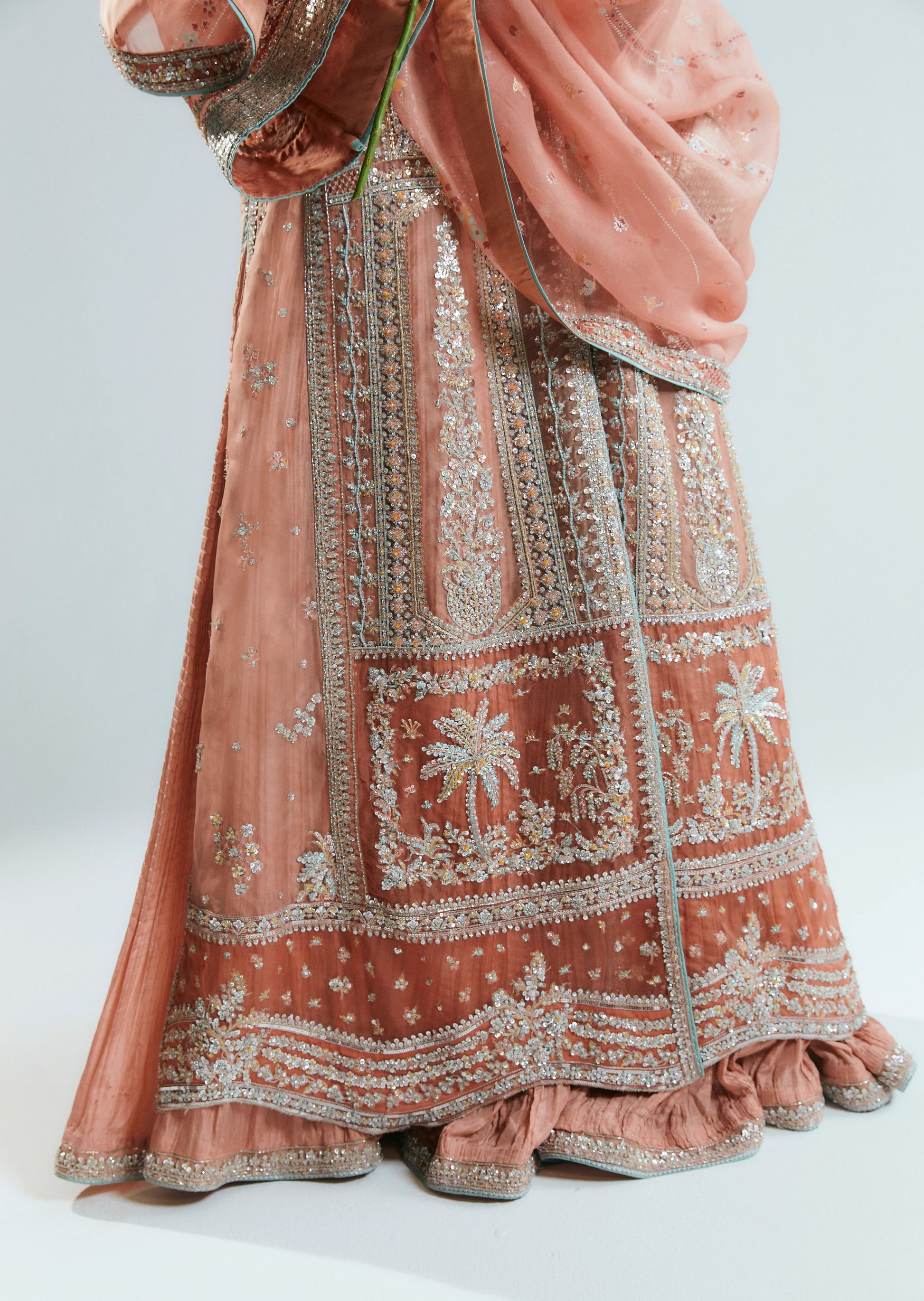 Traditional embroidered outfit with a pink and gold color scheme on a white background