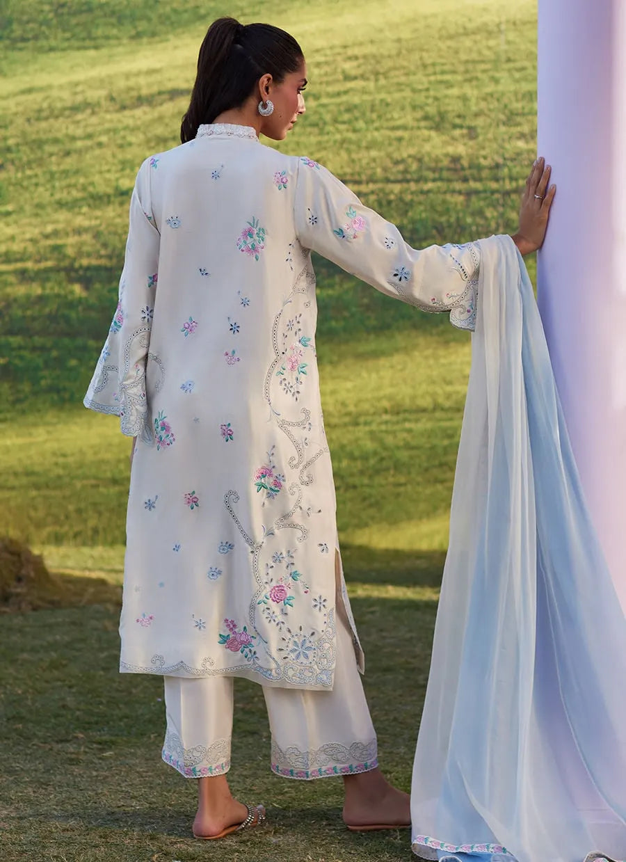 Woman in a white embroidered outfit standing in a grassy field