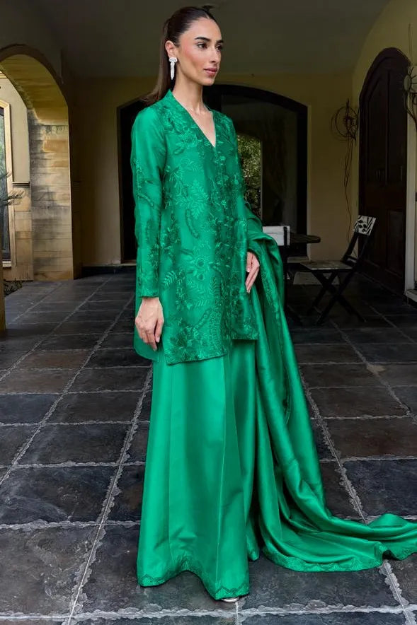 Woman in a green traditional outfit standing on a stone floor.
