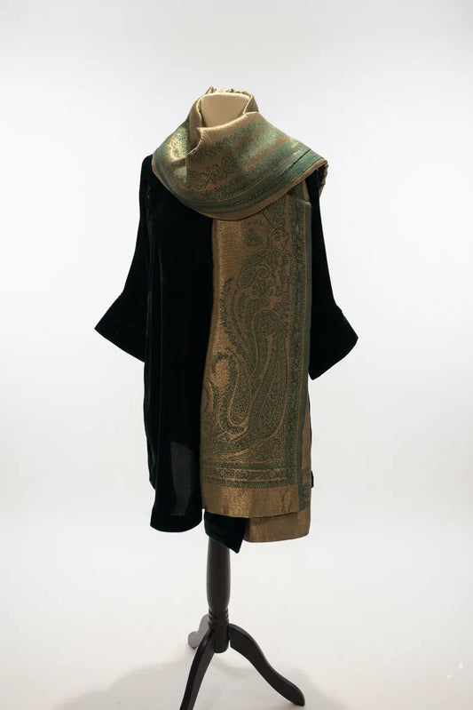 Mannequin wearing a dark coat with a green patterned scarf on a white background