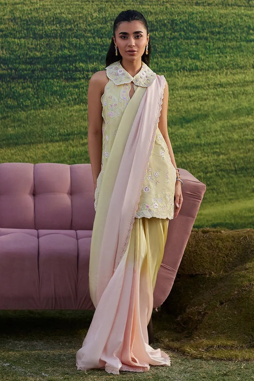 Woman in a light green outfit with a pink dupatta standing in a grassy field.