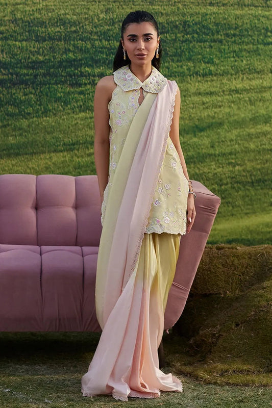 Woman in a light green outfit with a pink dupatta standing in a grassy field.