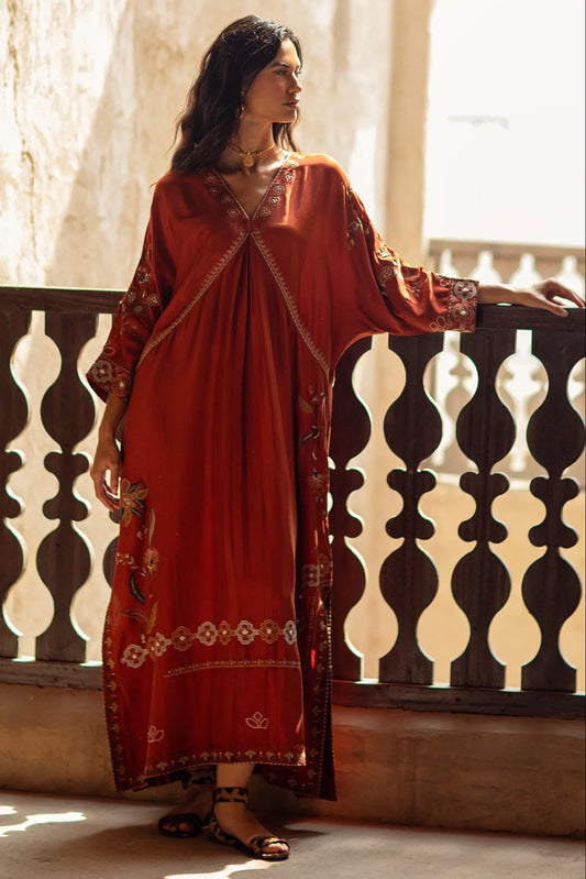 Woman in a red traditional outfit standing by a decorative railing.