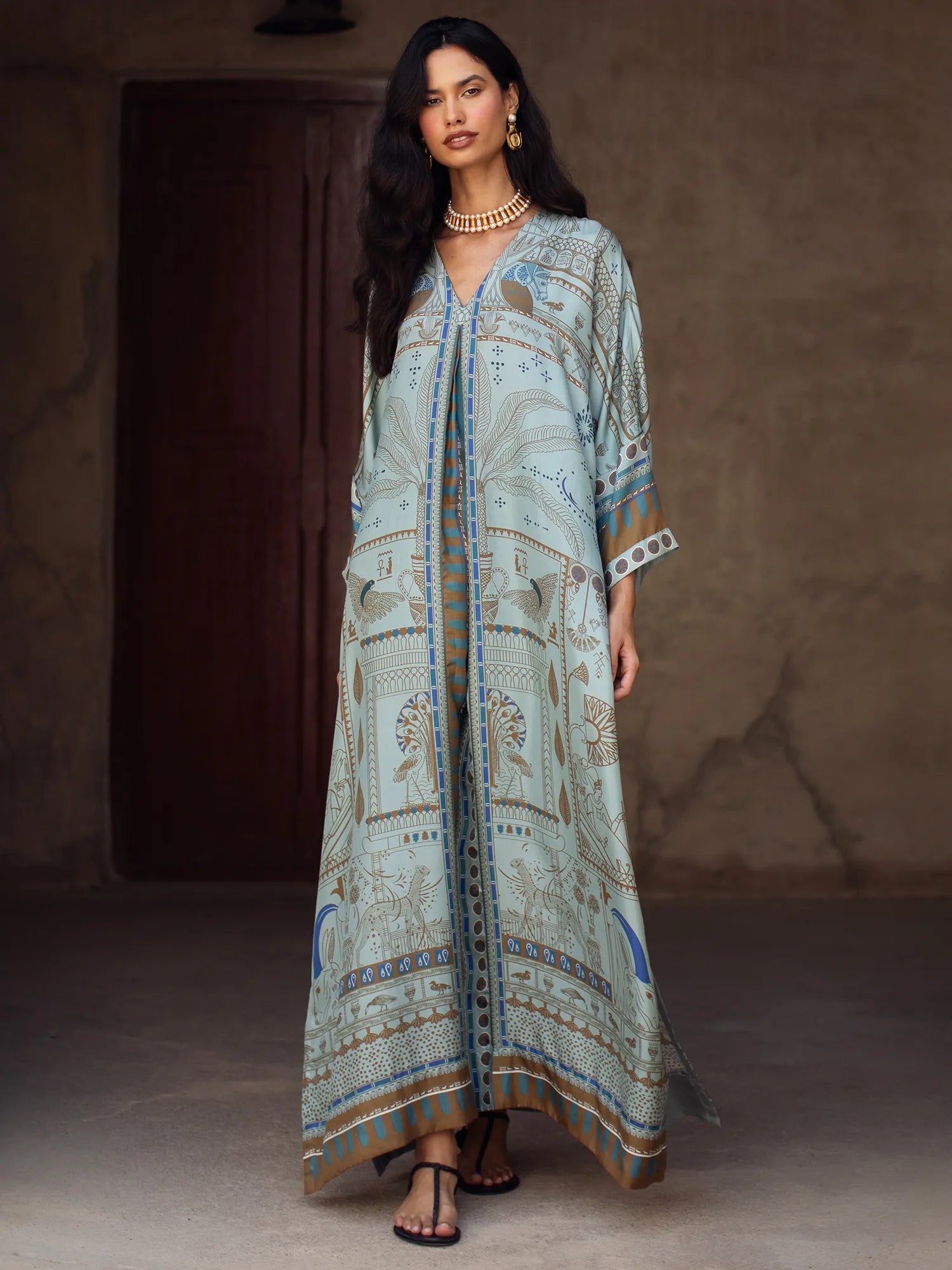 Woman wearing a long, patterned dress against a neutral background