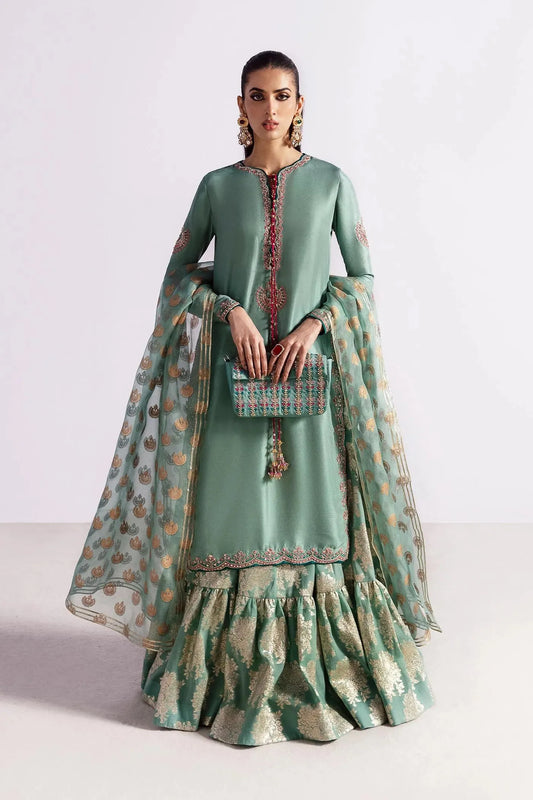 Woman wearing a traditional green outfit with a matching dupatta on a white background