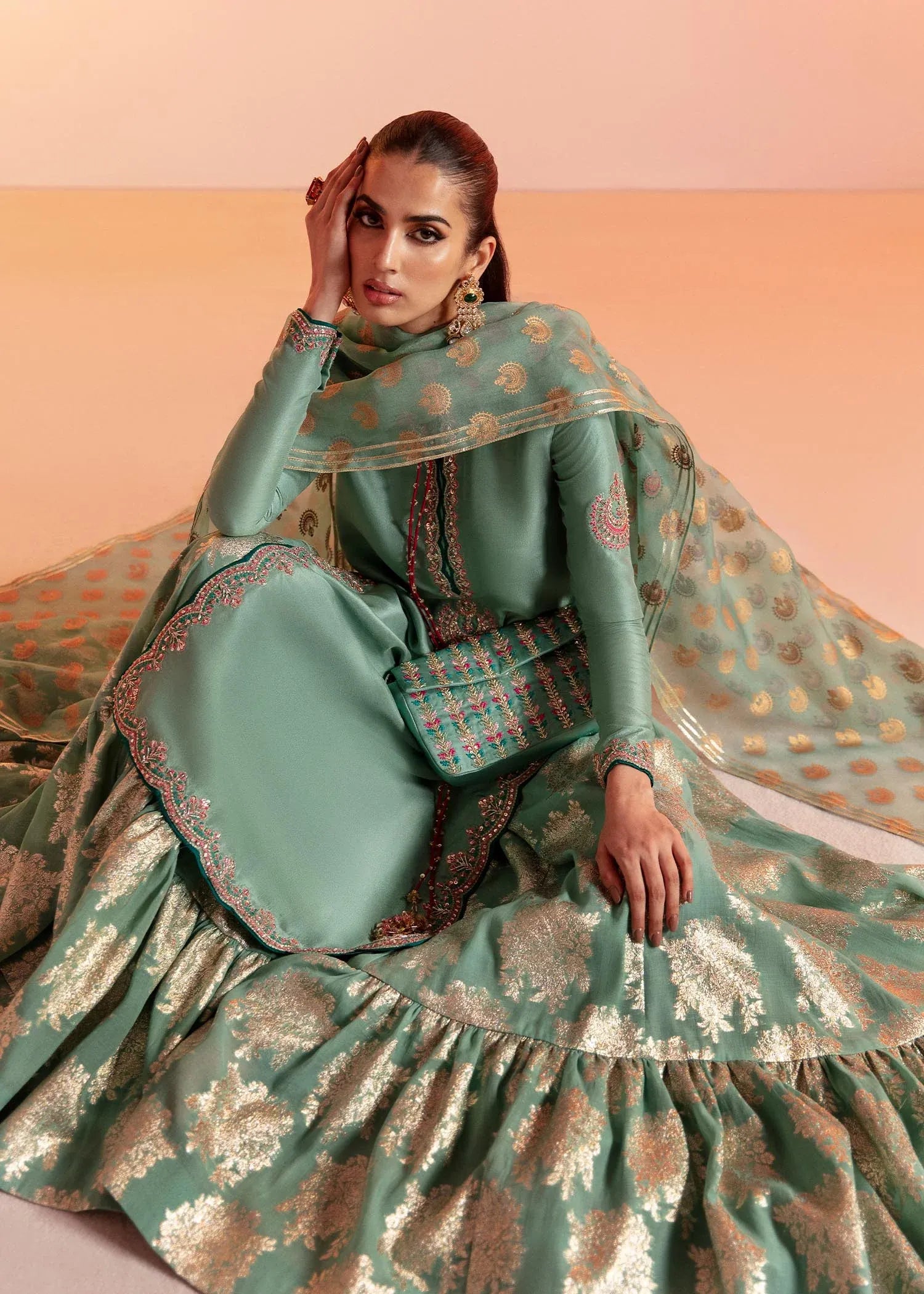 Woman wearing a traditional green and gold outfit with a plain background