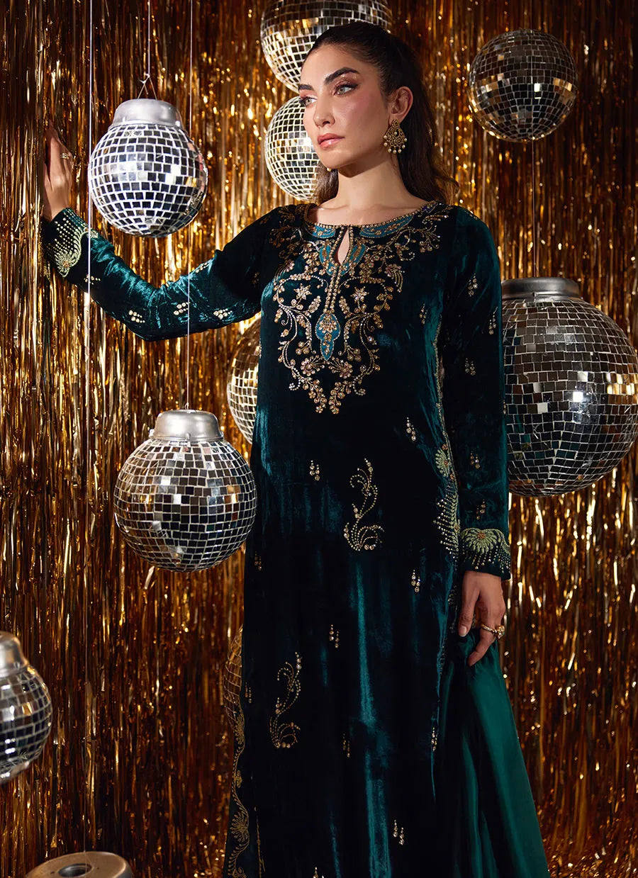 Woman in a green embroidered dress holding disco balls against a glittery gold background