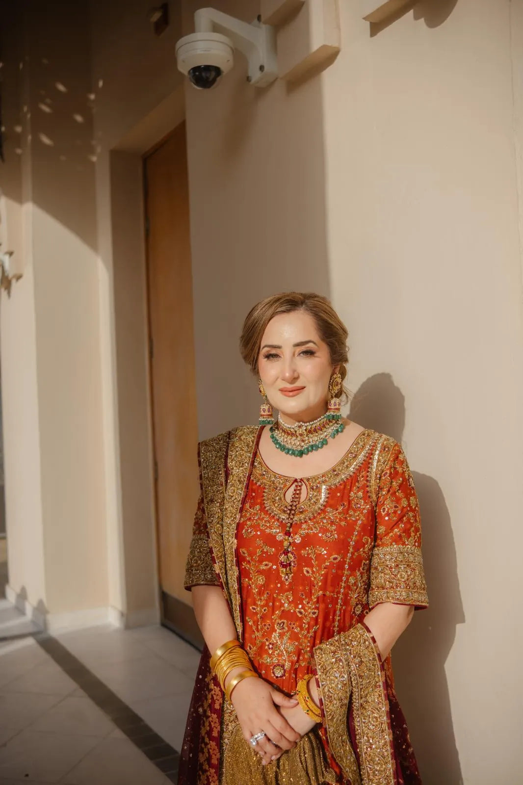 Woman in traditional attire standing indoors with a neutral background