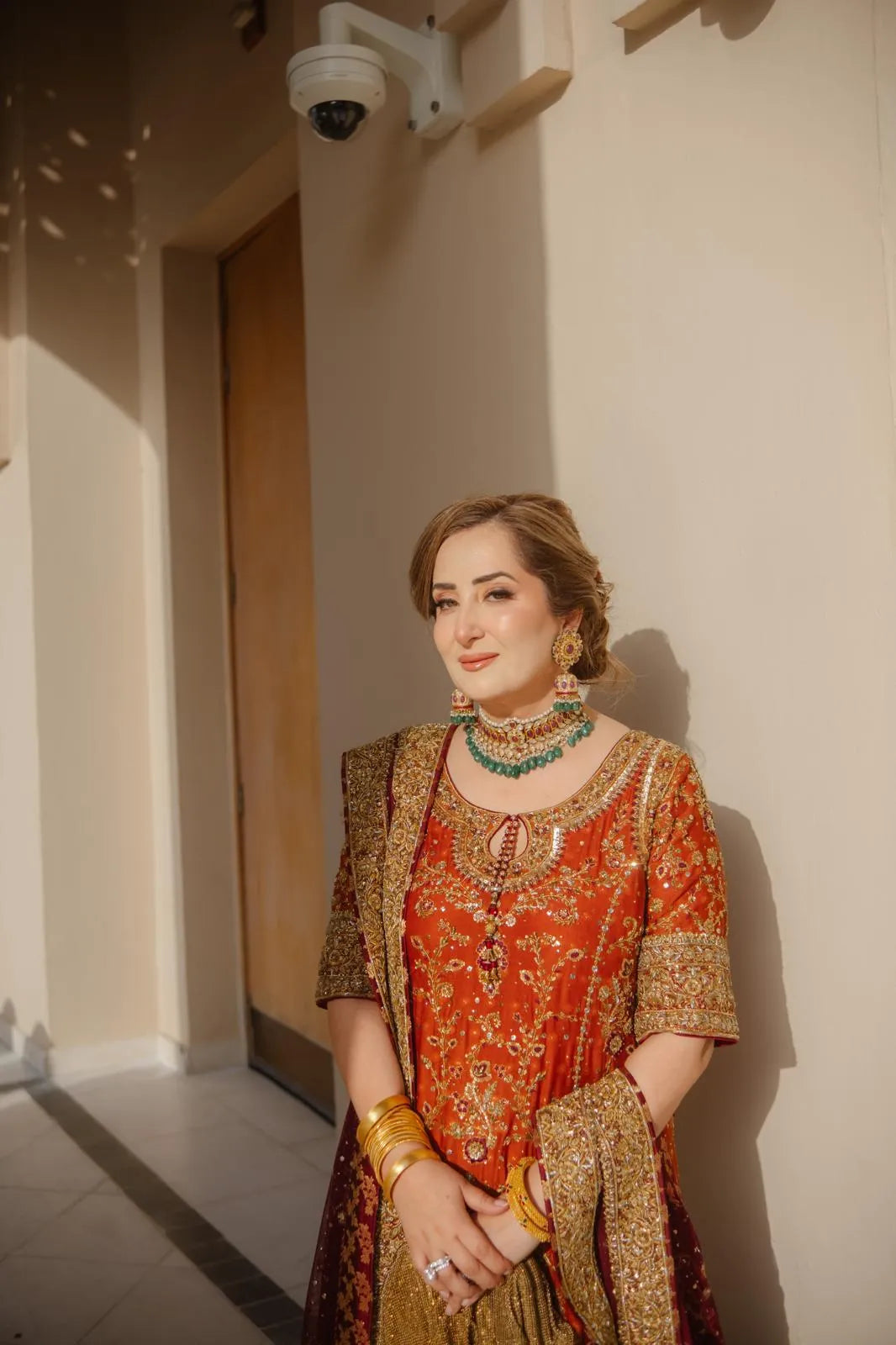 Woman in traditional attire standing indoors with a neutral background