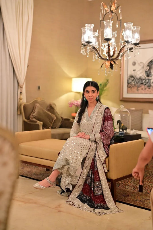 Woman in traditional attire sitting in a decorated room with a chandelier.