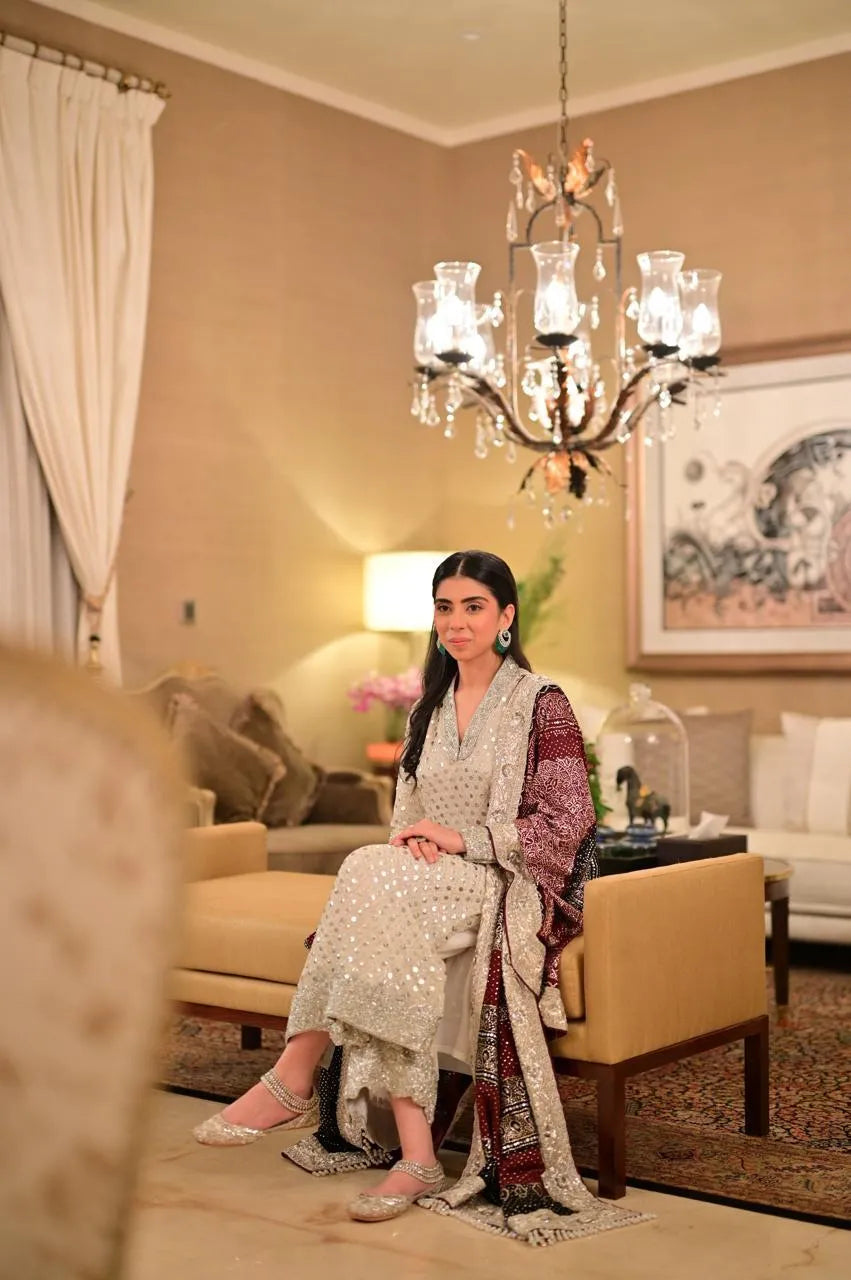 Woman sitting on a couch in a decorated living room with a chandelier.
