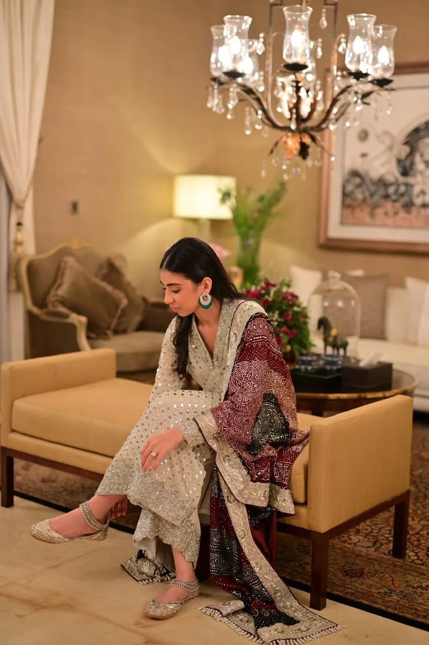 Woman in traditional attire sitting on a yellow couch in a decorated living room.